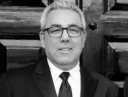 A man in suit and tie standing next to a wooden door.