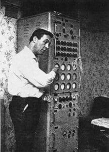 A man is standing in front of an old fashioned machine.