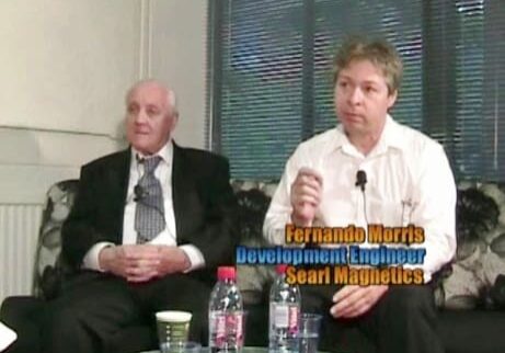 Two men sitting at a table with water bottles.